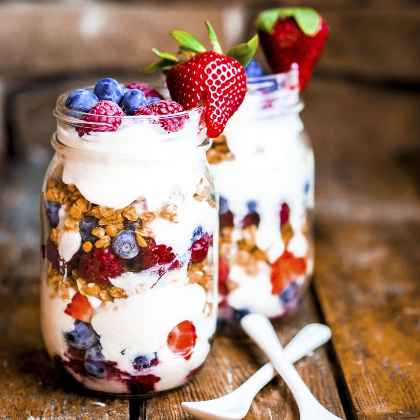 Granola Parfait with yogurt and berries on rustic background