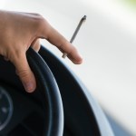 Close-up of a men driving and smoking joint