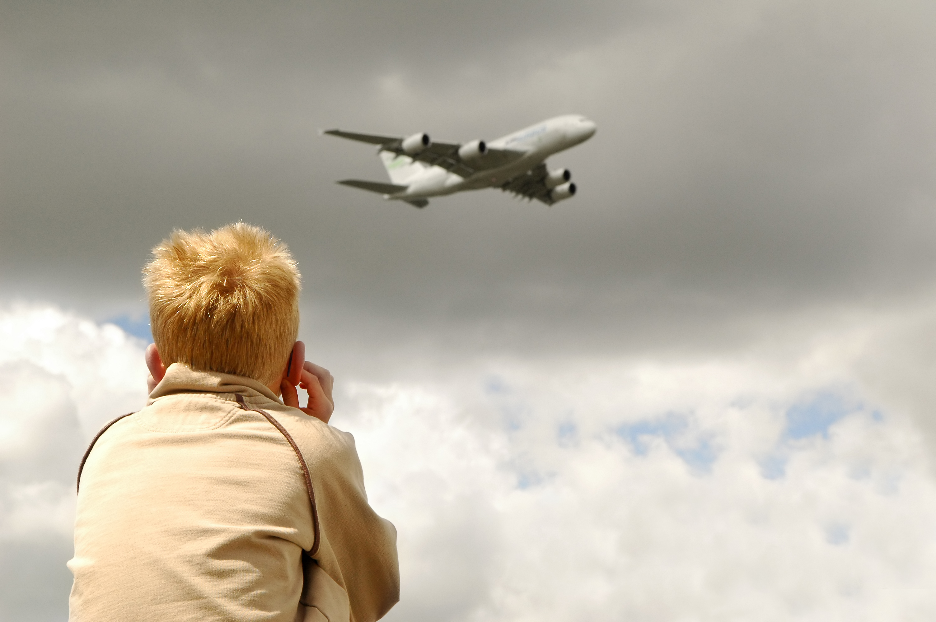 small child deafened by roar of a large jet aircraft overhead