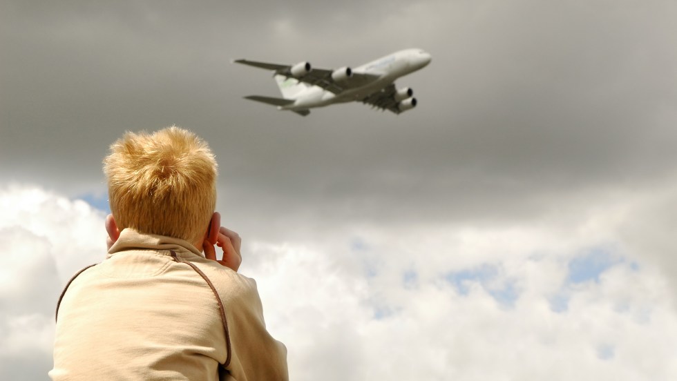 small child deafened by roar of a large jet aircraft overhead