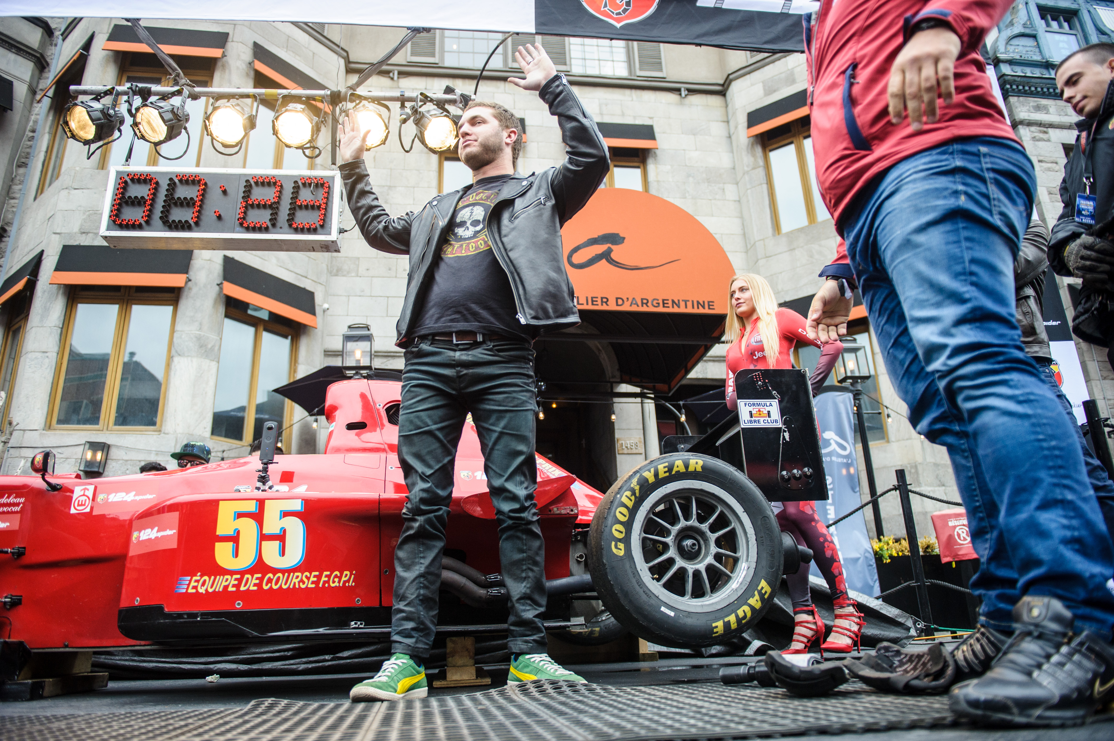 Des hommes se tiennent devant une voiture de course pendant le Festival Grand Prix sur Crescent.