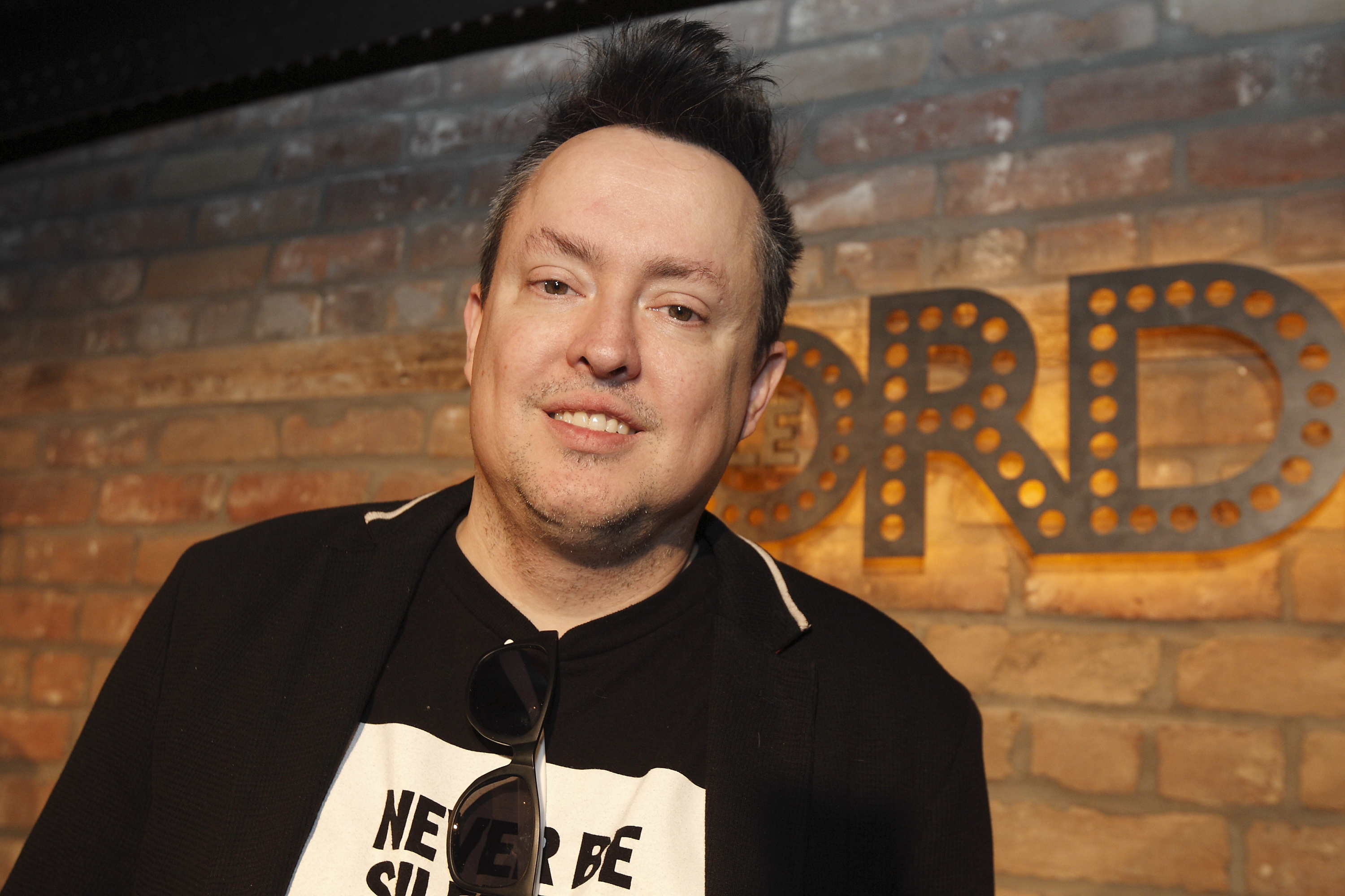 Mike Ward devant un mur de brique