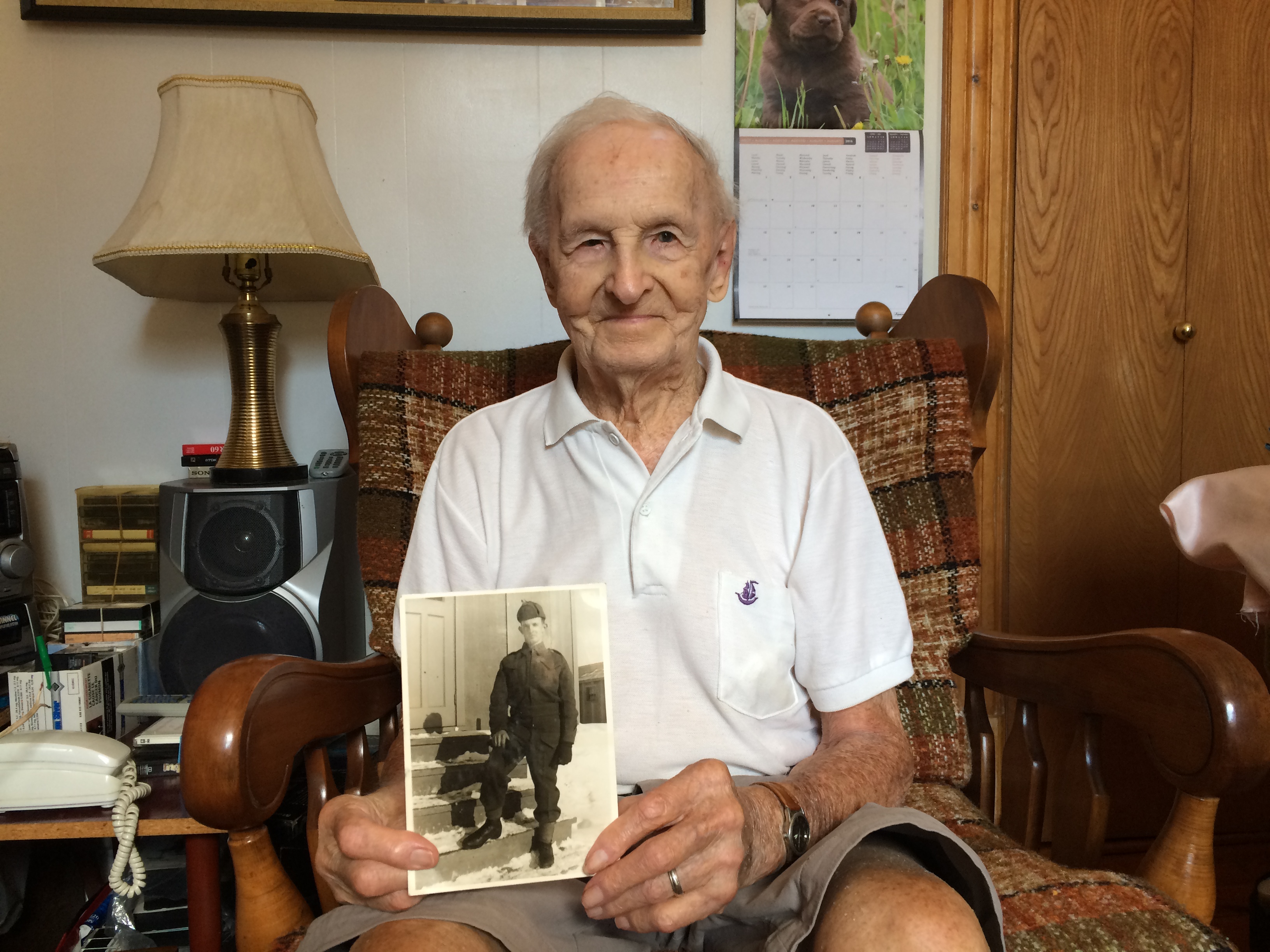 Charles-Édouard Gauthier pose avec une photo prise en 1941 à la sortie de son service militaire à Sherbrooke.