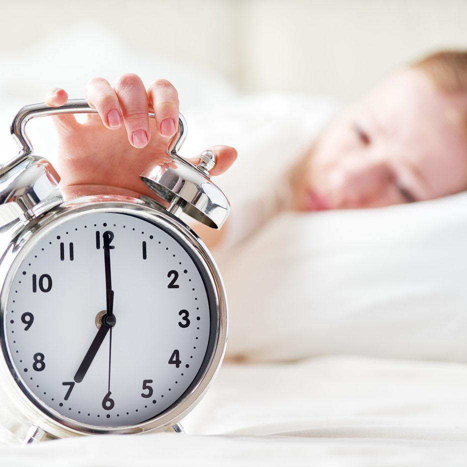 the alarm clock and a sleeping young woman