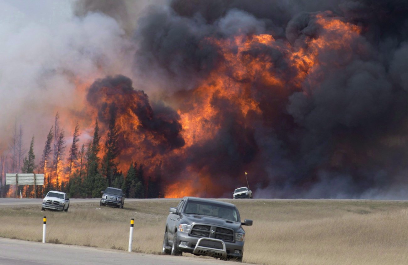 A giant fireball is seen as a wild fire rips through the forest 16 km south of Fort McMurray, Alberta on highway 63 Saturday, May 7, 2016. The ferocious wildfire that forced nearly 90,000 to flee Canada's oilsands region and reduced thousands of homes to rubble has been picked as the top news story of 2016 in an annual survey of newsrooms across Canada by The Canadian Press. THE CANADIAN PRESS/Jonathan Hayward