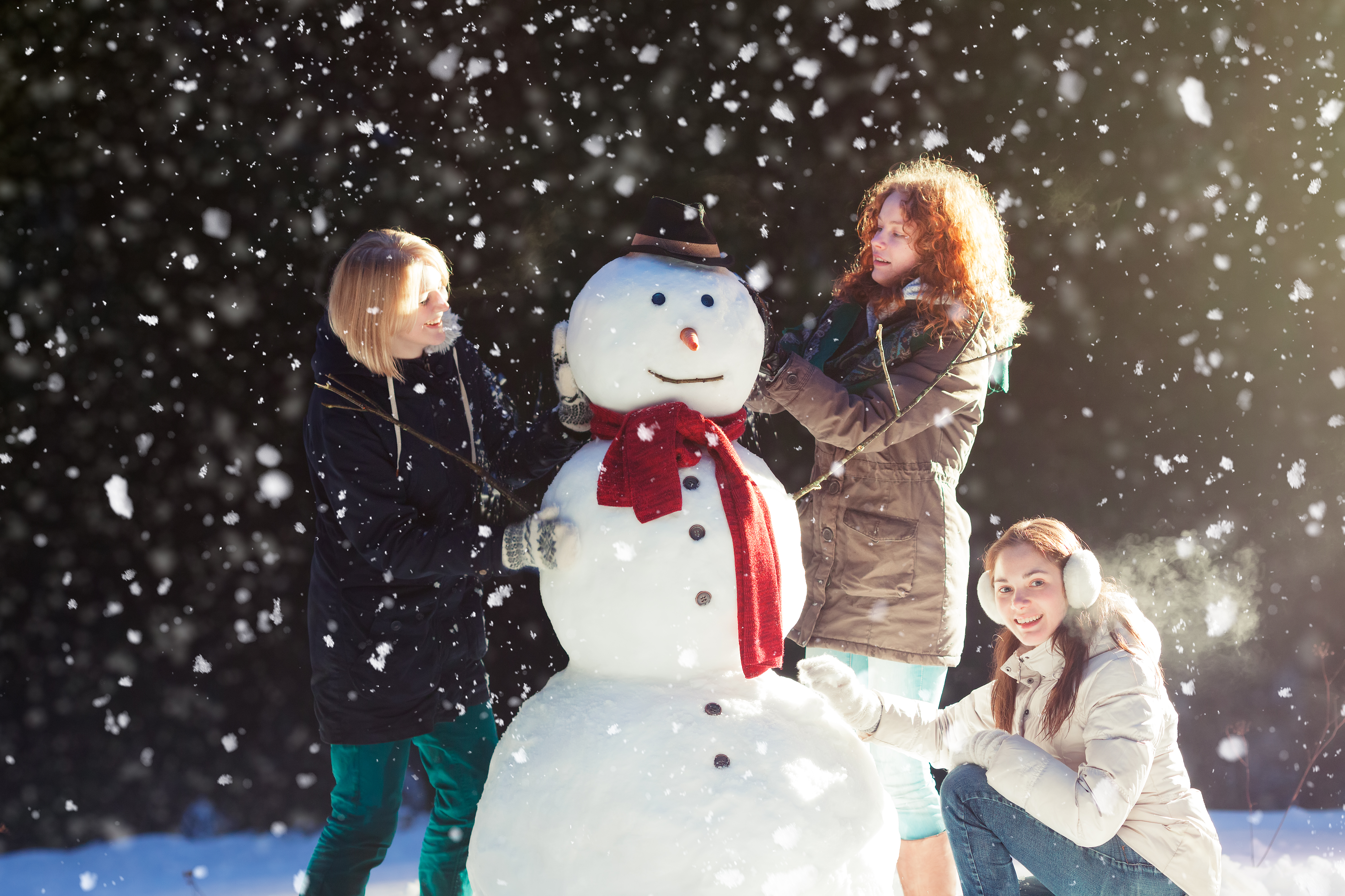 De jeunes femmes construisent un bonhomme de neige.