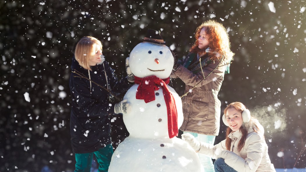 De jeunes femmes construisent un bonhomme de neige.