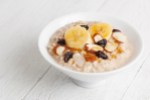 Healthy breakfast oatmeal bowl with bananas, almonds, raisins and honey