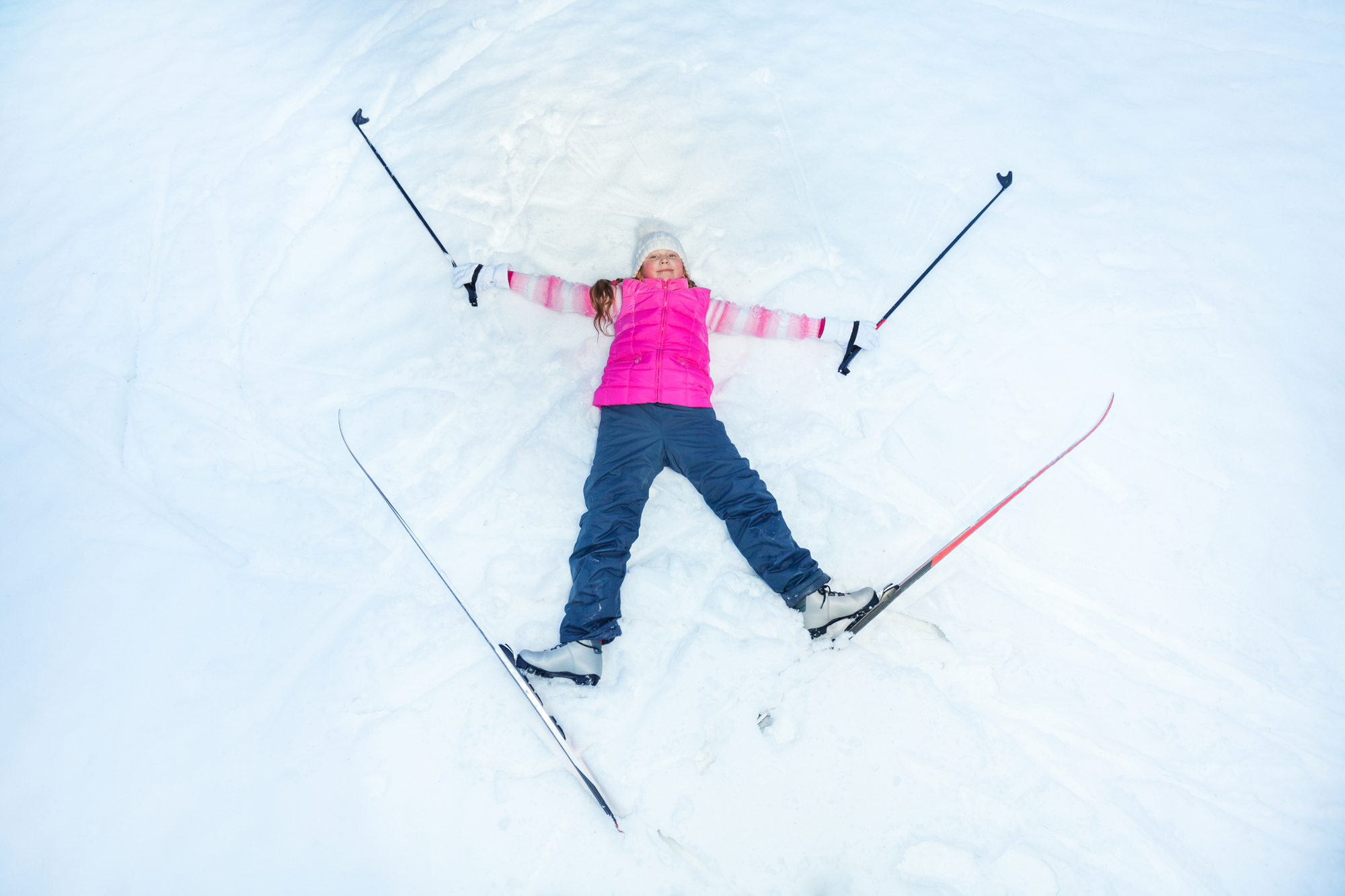 Happy skier with skis an sticks laying on the snow as a star, top view