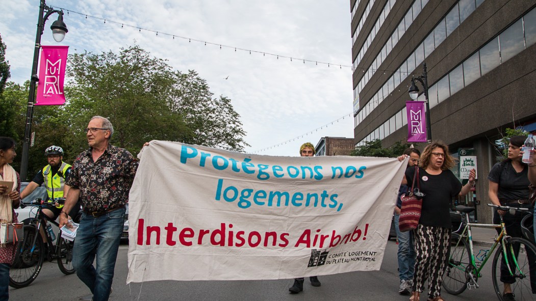 Des manifestants défilent avec une pancarte indiquant «Protégeons nos logements, interdissons Airbnb».