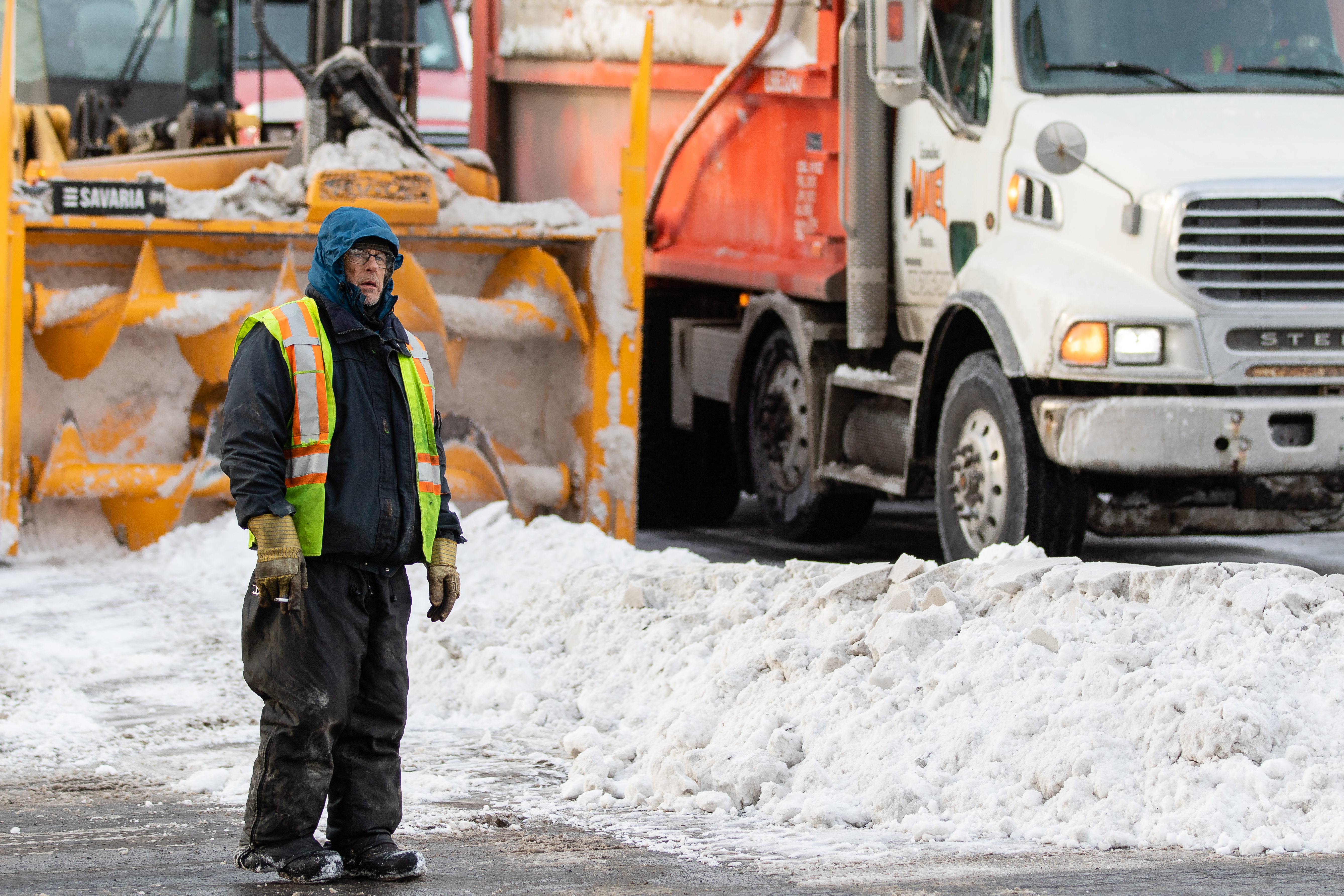 Un travailleur se trouve devant un camion de déneigement