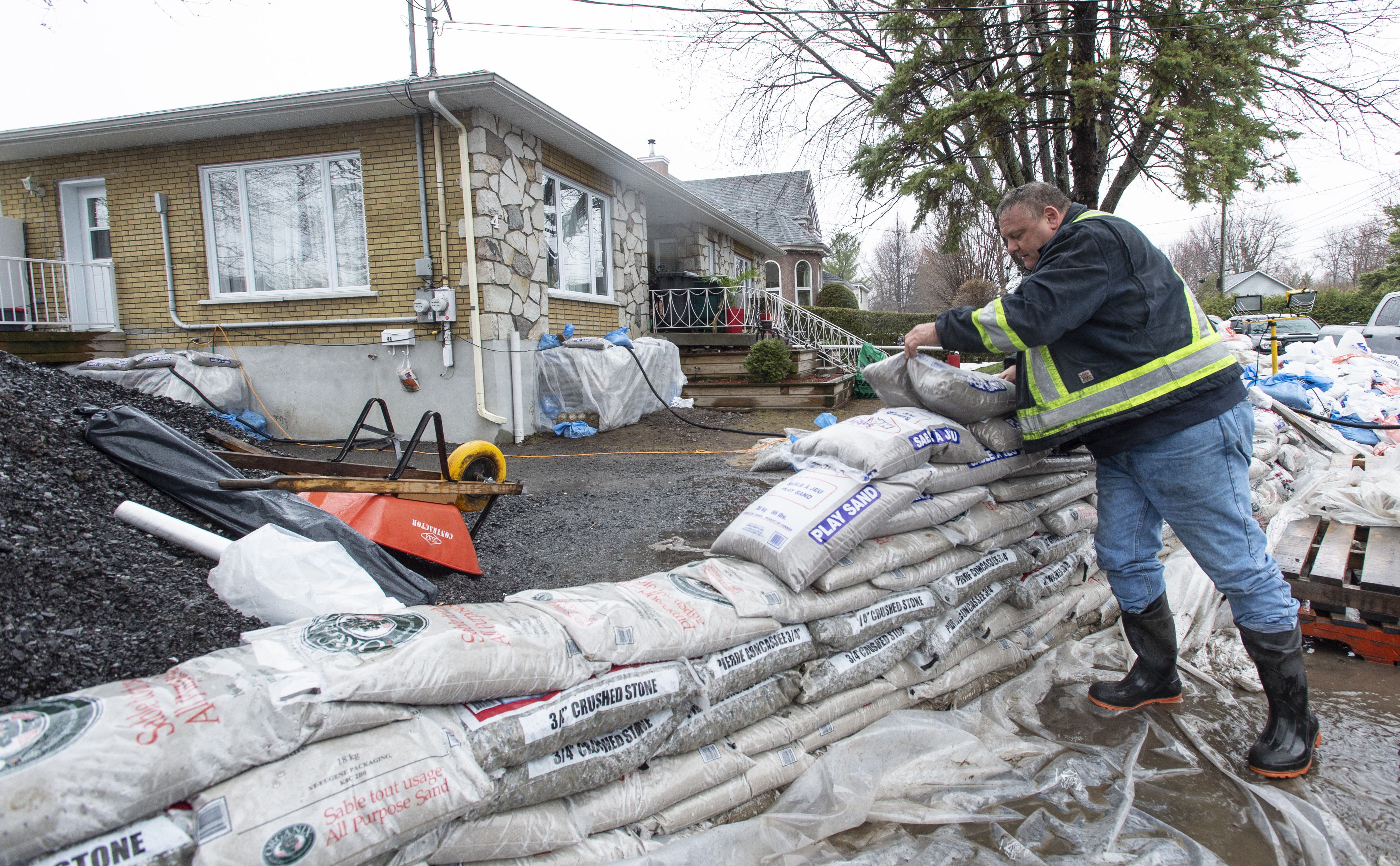 Un travailleur pose des sac de sable lors d'une inondation