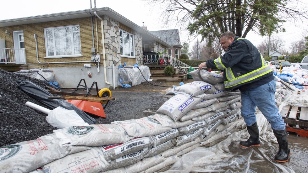 Un travailleur pose des sac de sable lors d'une inondation