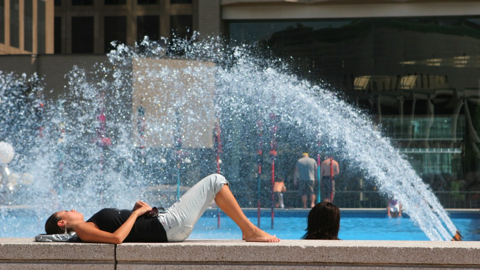 Une femme se rafraîchit sur le bord d'un bassin à Montréal.