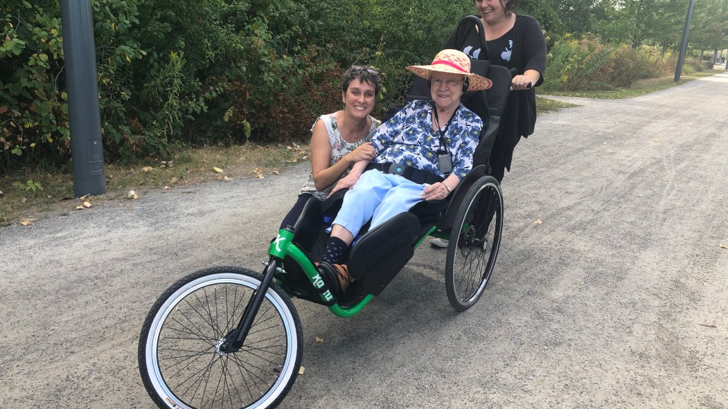 Lilianne Boulay, 94 ans, est promenée à vélo par l’ergothérapeute Chantal Lambert (gauche) et la technicienne en loisirs Isabelle Dufresne (droite)