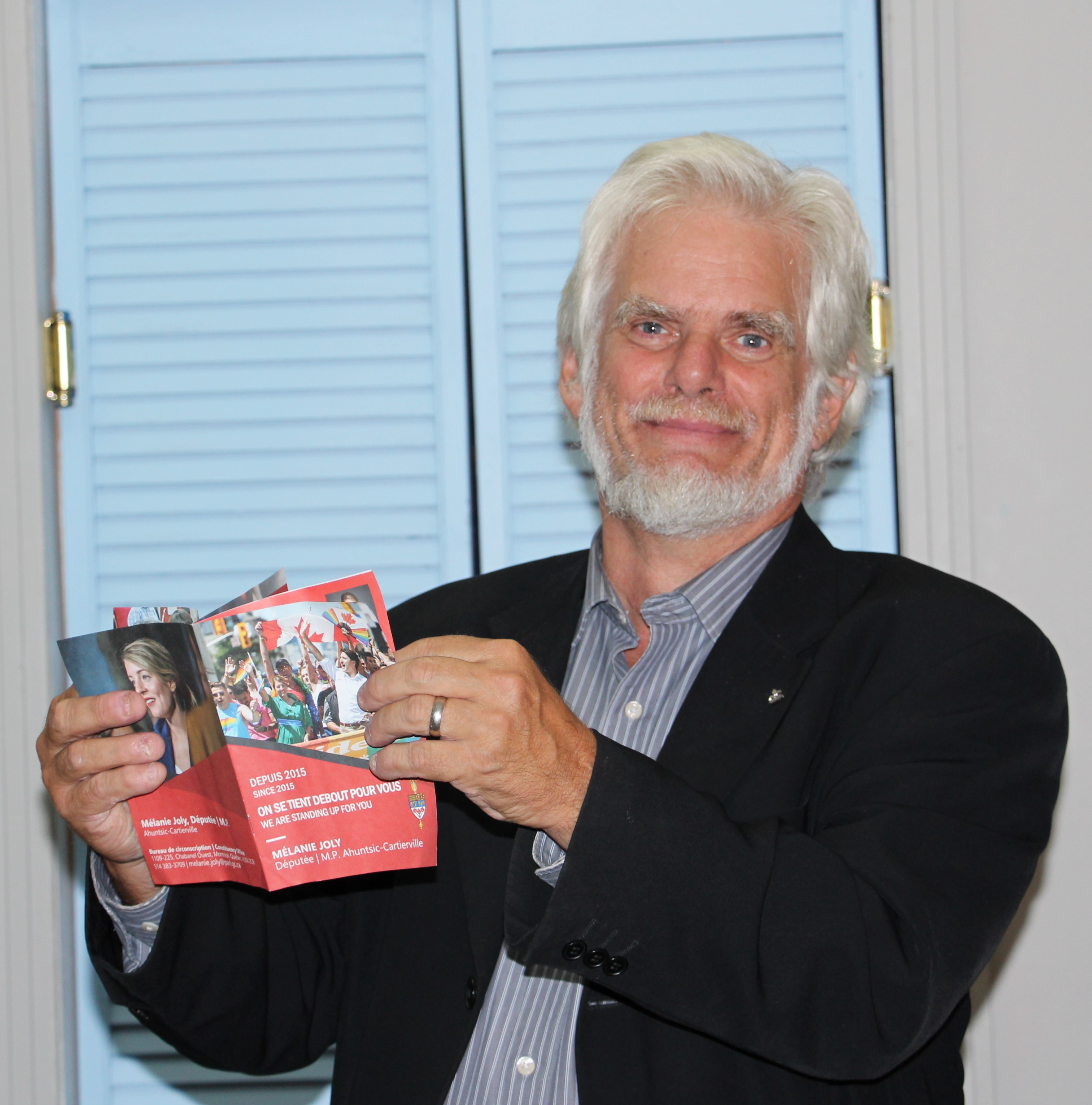 André Parizeau candidat du Bloc Québécois lisant un dépliant de Mélanie Joly, candidate du Parti libéral