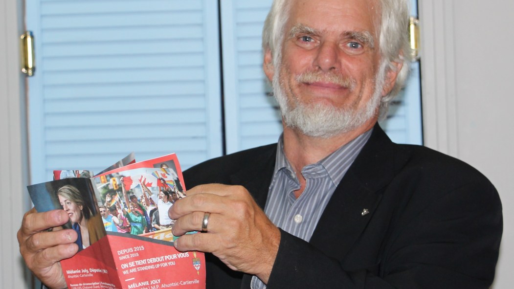 André Parizeau candidat du Bloc Québécois lisant un dépliant de Mélanie Joly, candidate du Parti libéral