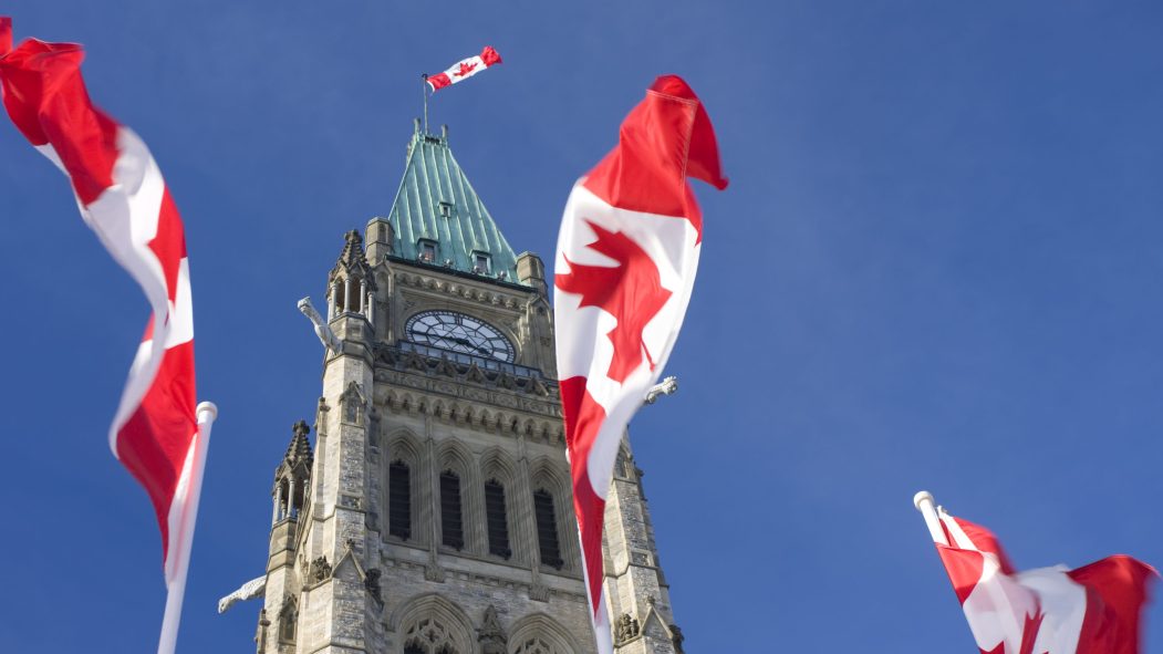 Le parlement et trois drapeaux du Canada