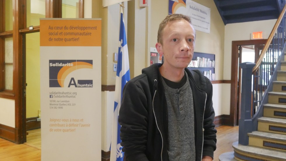 Rémy Robitaille directeur de Solidarité Ahuntsic devant une bannière.