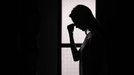 Silhouette d'un jeune homme qui se tient la tête comme signe d'anxiété.