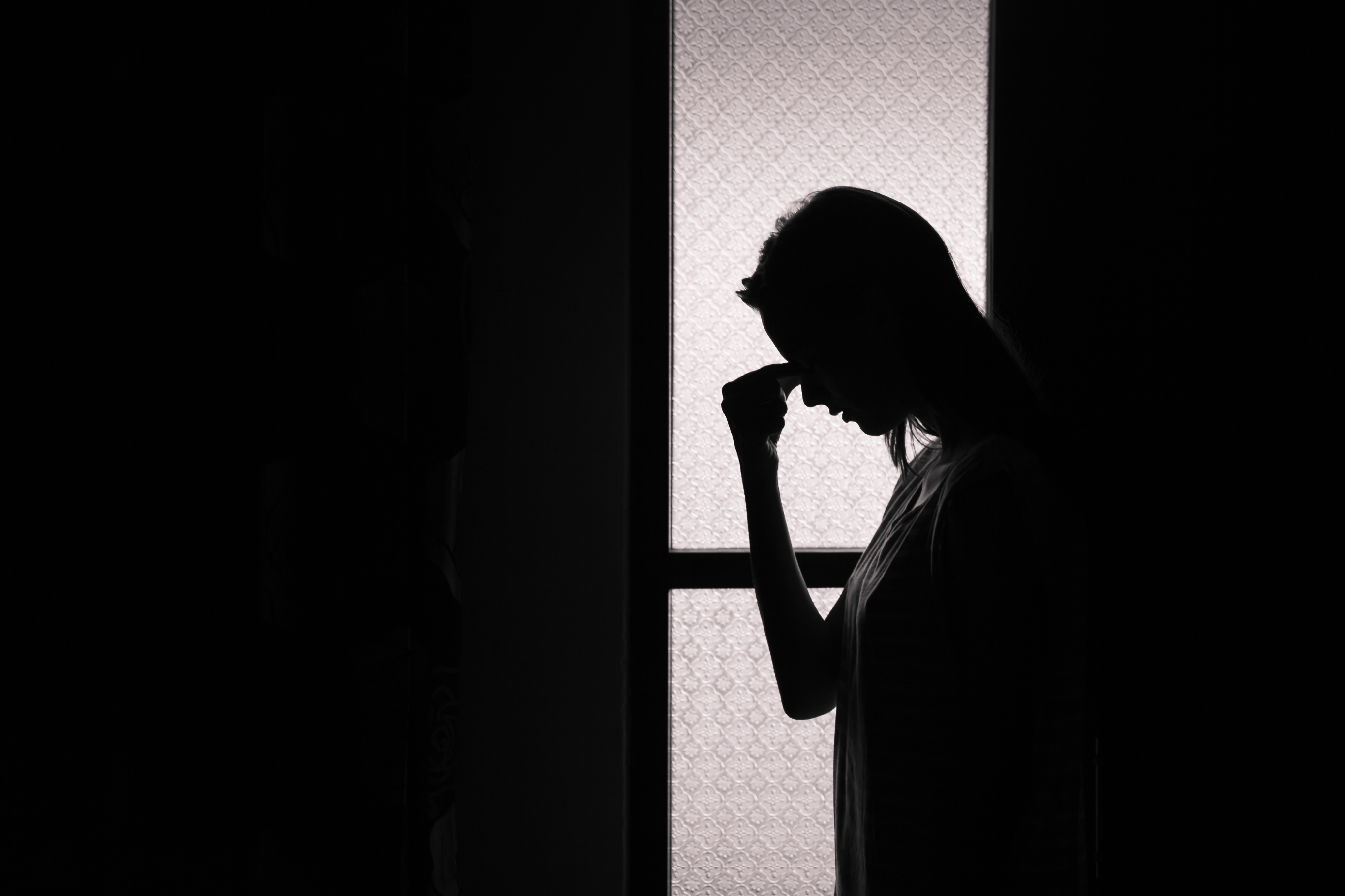 Silhouette d'un jeune homme qui se tient la tête comme signe d'anxiété.
