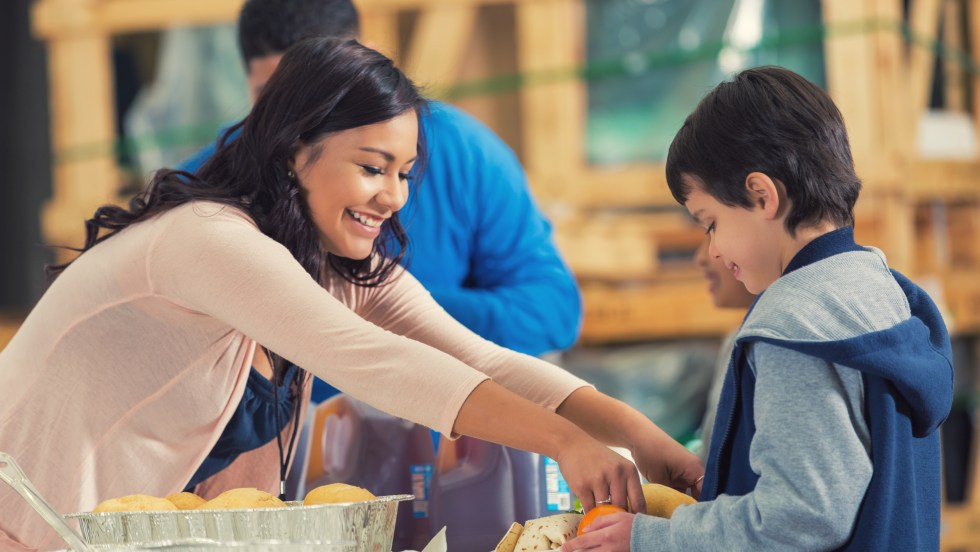 Une jeune femme sert un repas dans une soupe populaire, dans le cadre d'un projet d'entrepreneuriat social