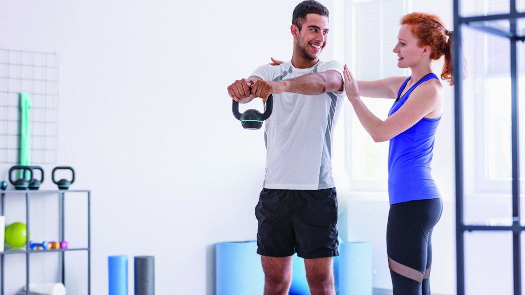 Une kinésiologue aide un athlète avec un mouvement de musculation.