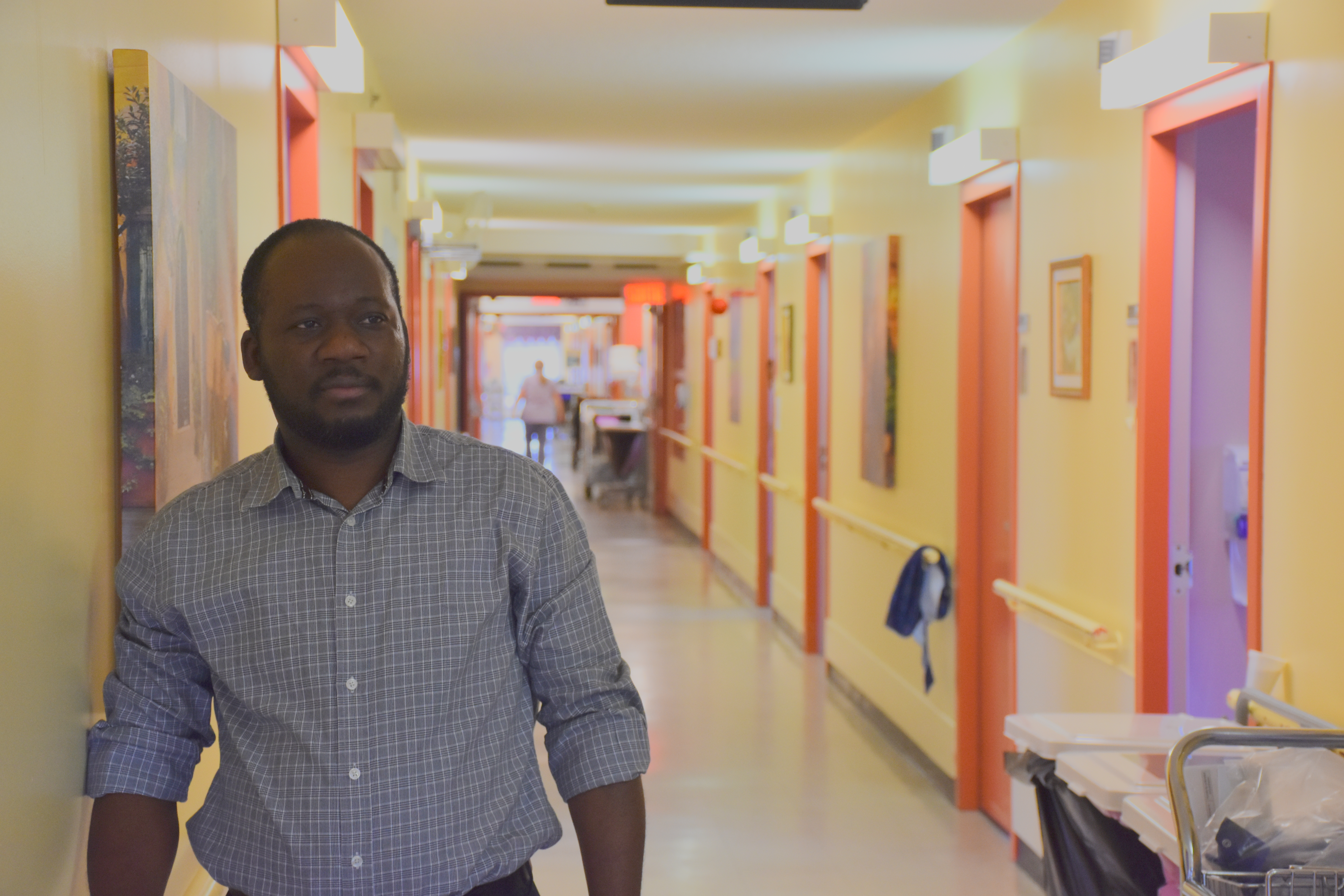 Un préposé aux bénéficiaires regarde au loin dans un couloir de CHSLD