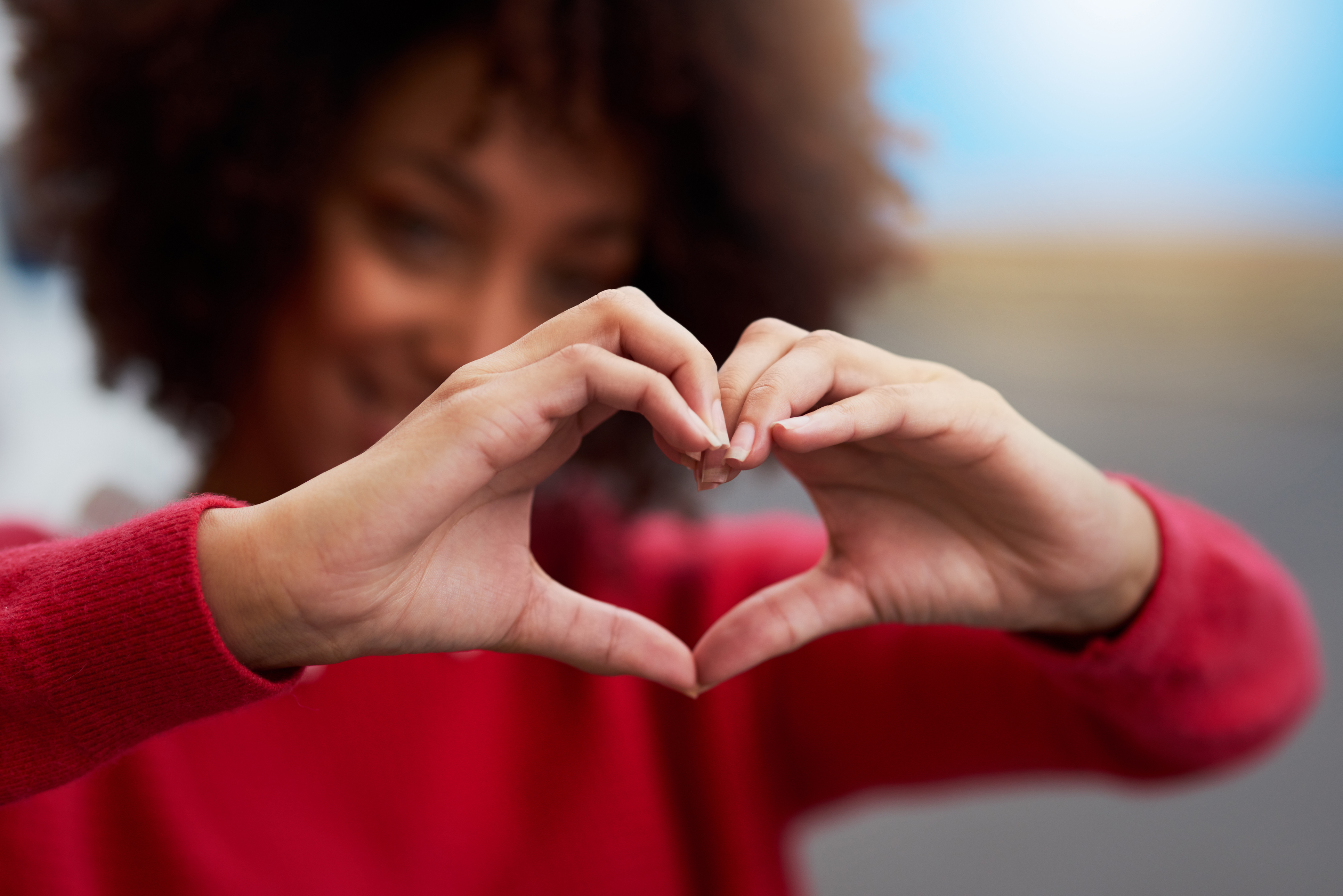 Une femme forme un coeur avec ses mains en signe d'amour.