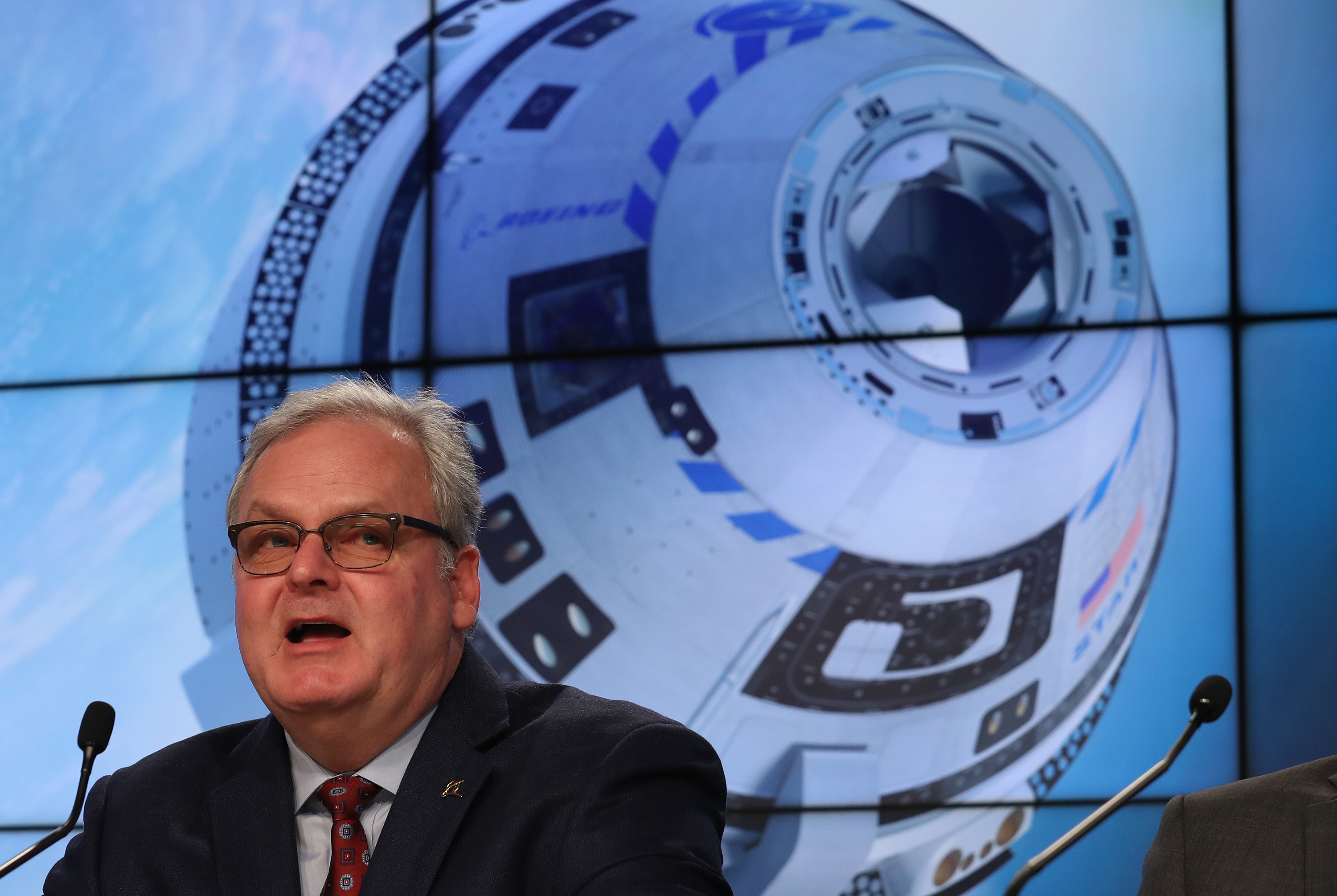 Jim Chilton, vice-président sénior de Boeing, devant une grande affiche de la capsule Starliner.