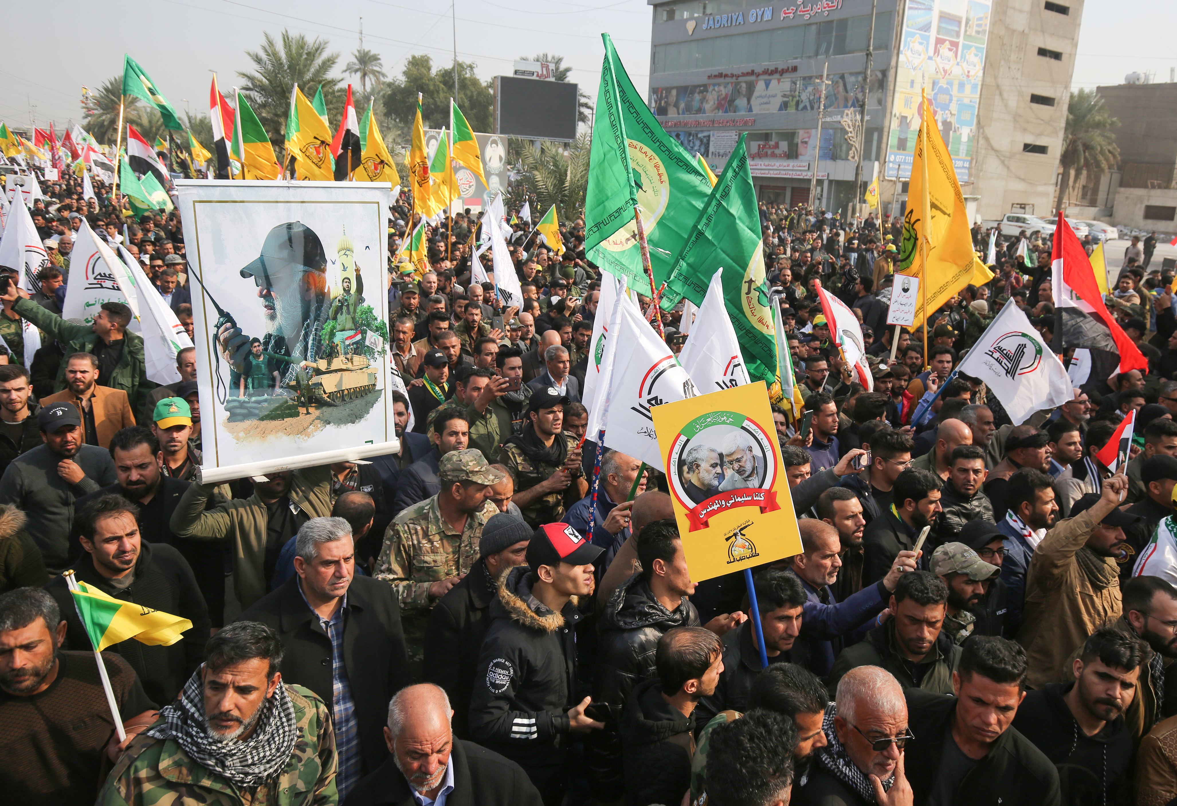 Une foule d'irakiens tenant des drapeaux du Hachd et du Hezbollah lors des obsèques du général iranien Qassem Soleimani, à Bagdad, le 4 janvier 2020.