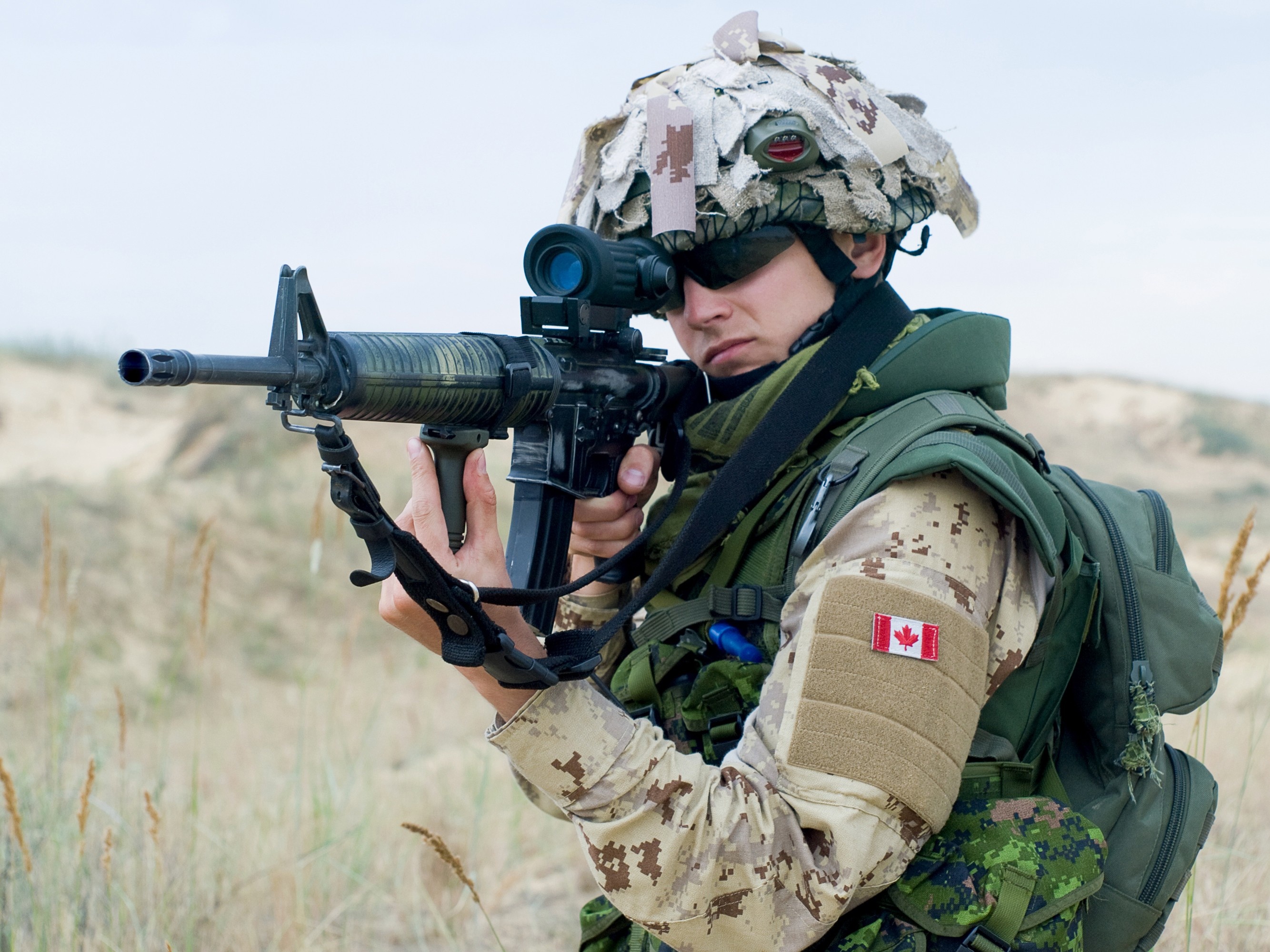Un soldat de l'armée canadienne en Irak, portant du camouflage de désert et pointant son arme