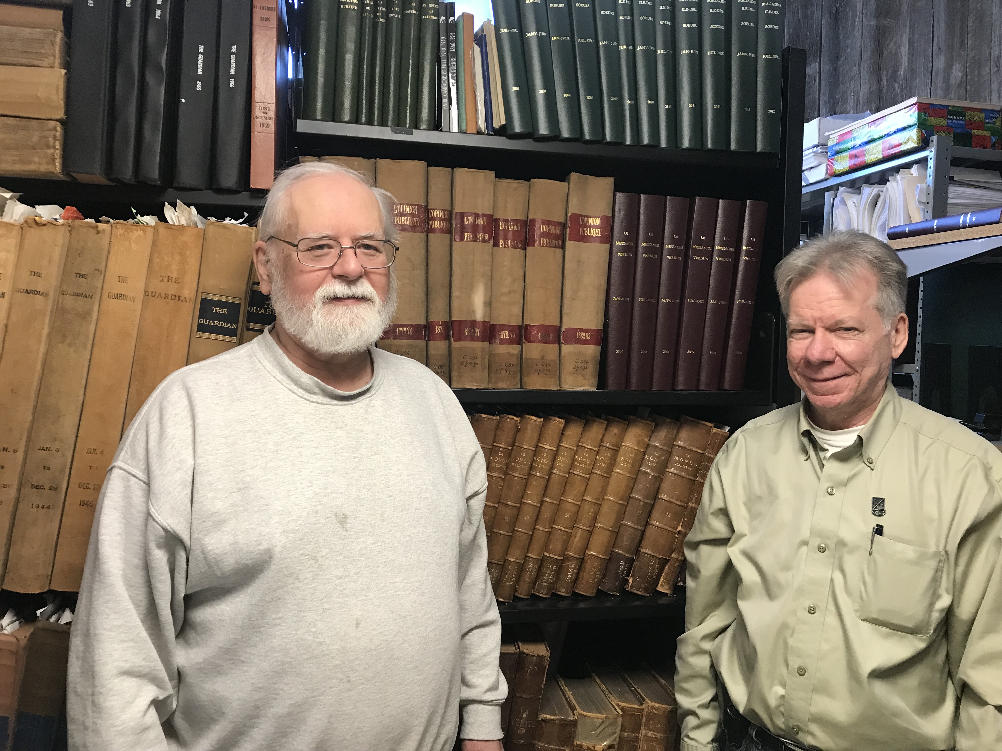 Gilles Lepage et Serge Bousquet se tiennent devant une bibliothèque de livres anciens.