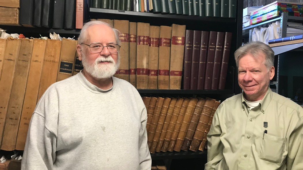 Gilles Lepage et Serge Bousquet se tiennent devant une bibliothèque de livres anciens.
