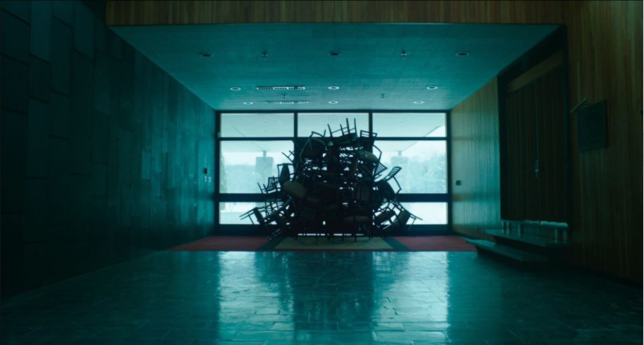 Des chaises sont baricadées devant une grande fenêtre.