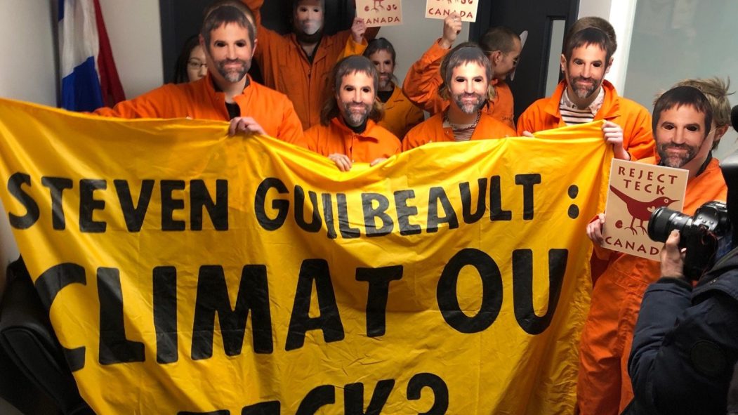Des militants écologistes habillés en combines oranges occupent les bureaux du ministre du Patrimoine Steven Guilbeault. Ils portent des masques à l'effigie du ministre.
