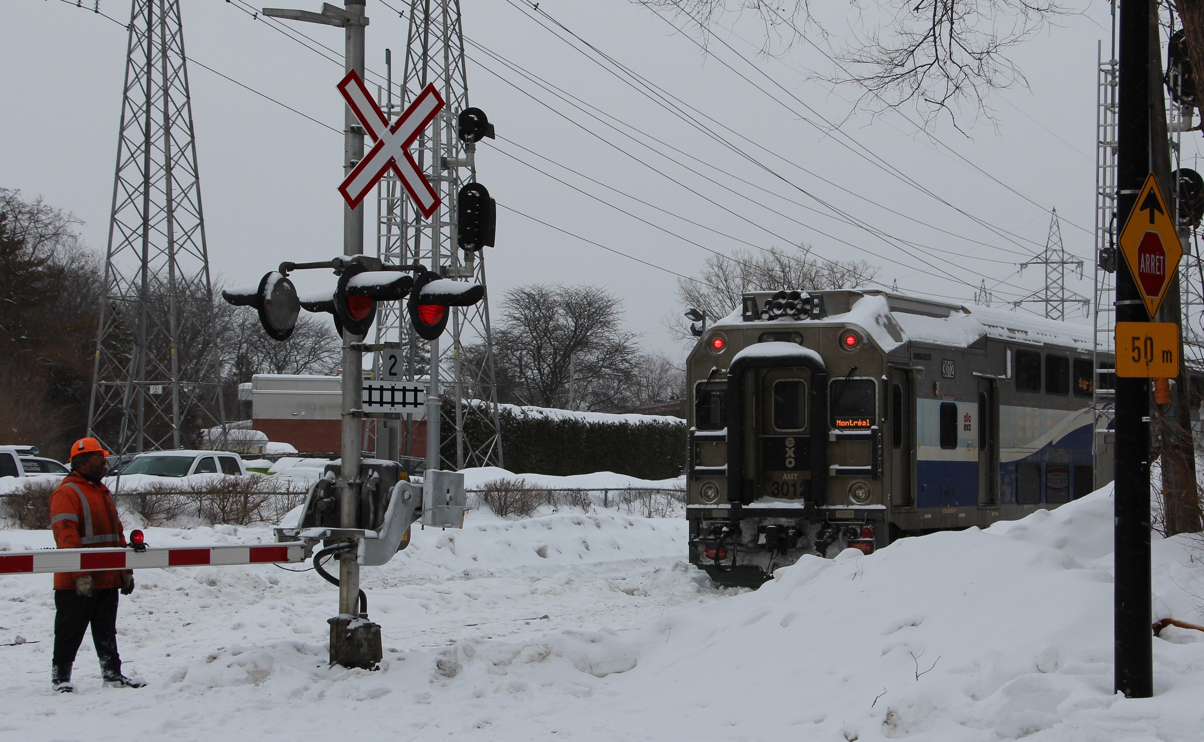 Train de banlieue immobilisé près d'un passage à niveau