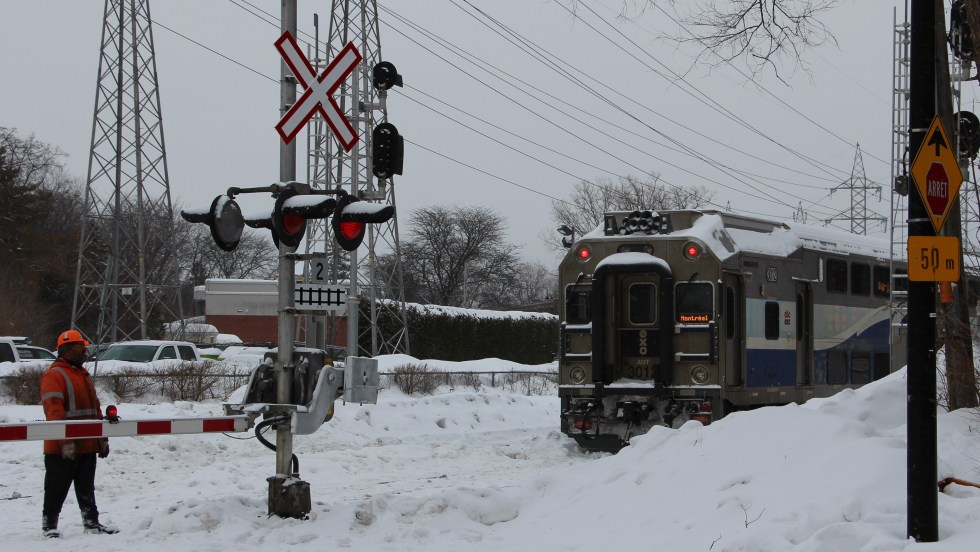 Train de banlieue immobilisé près d'un passage à niveau