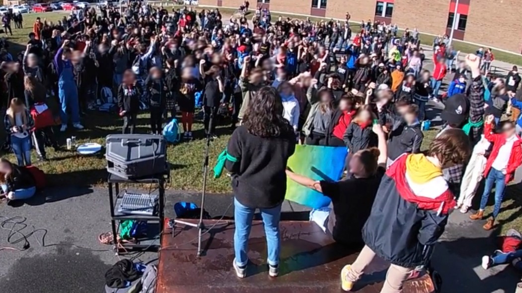 Une foule d'élèves d'une école secondaire lève le poing lors d'un vote portant sur la grève du climat.