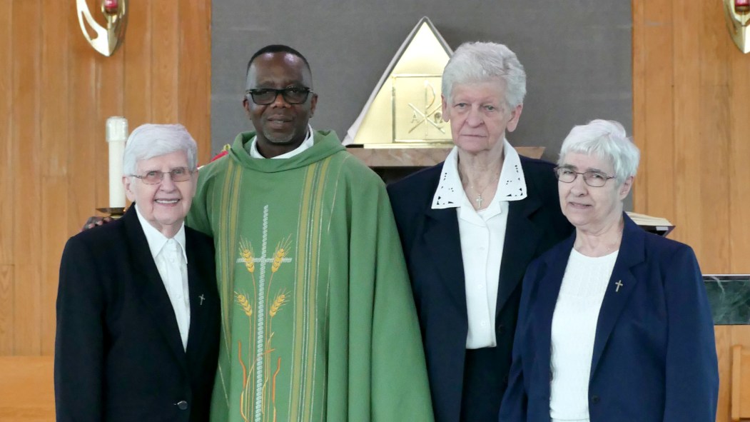 Père Jean Louis Nvougbia au milieux de trois membres de la congrégation religieuse des soeurs de miséricorde