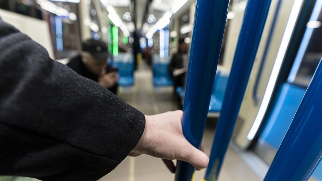 Une personne tient une barre dans un wagon de métro.