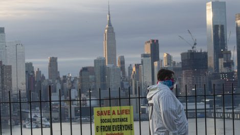 Un homme se couvre le visage alors que le soleil se lève au-dessus de New York le 6 avril 2020, vu depuis Weehawken au New Jersey.