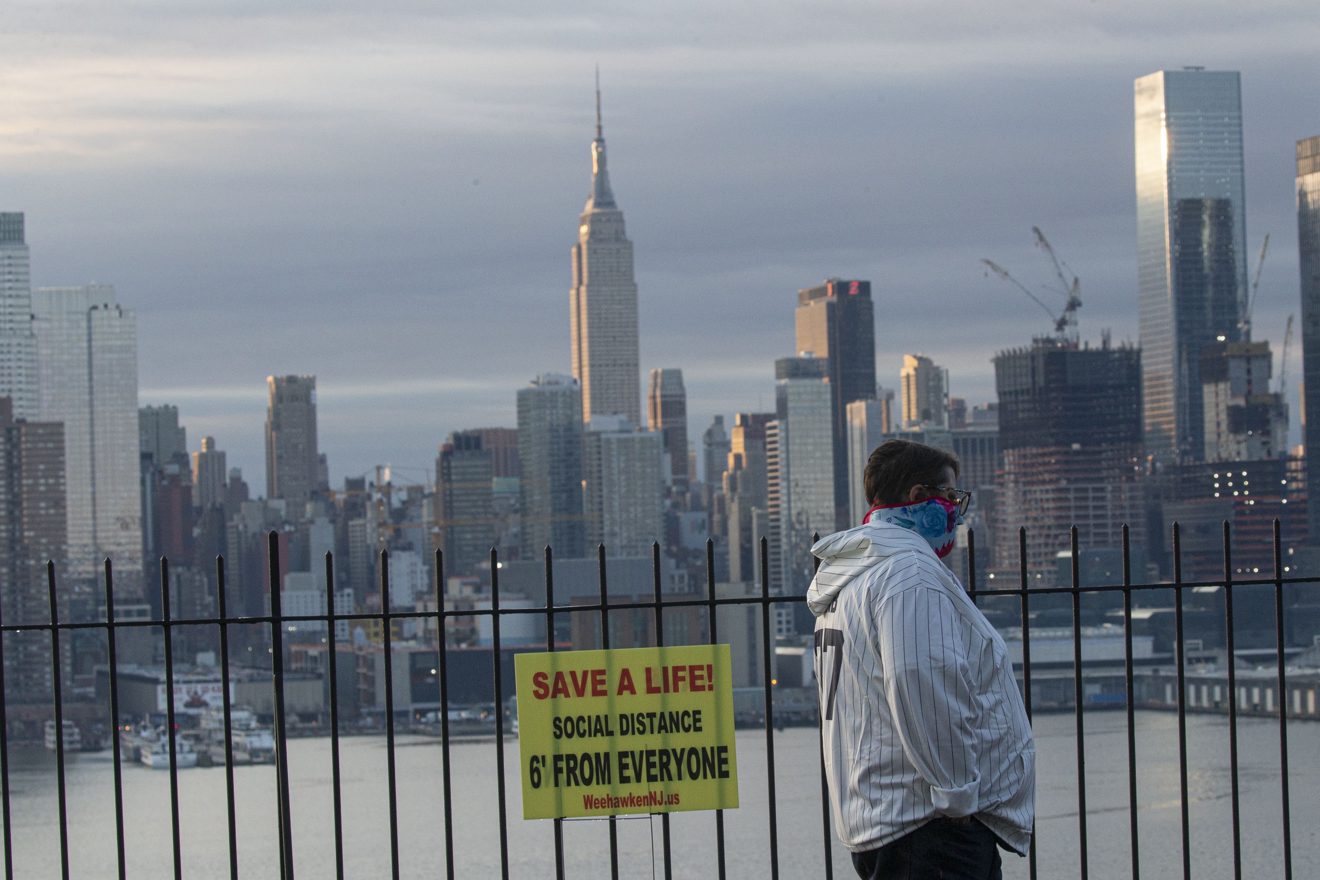 Un homme se couvre le visage alors que le soleil se lève au-dessus de New York le 6 avril 2020, vu depuis Weehawken au New Jersey.