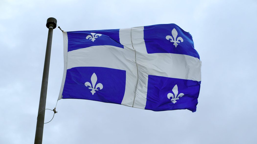 Un fleurdelysé, drapeau national du Québec, flottant devant un ciel nuageux