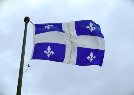Un fleurdelysé, drapeau national du Québec, flottant devant un ciel nuageux
