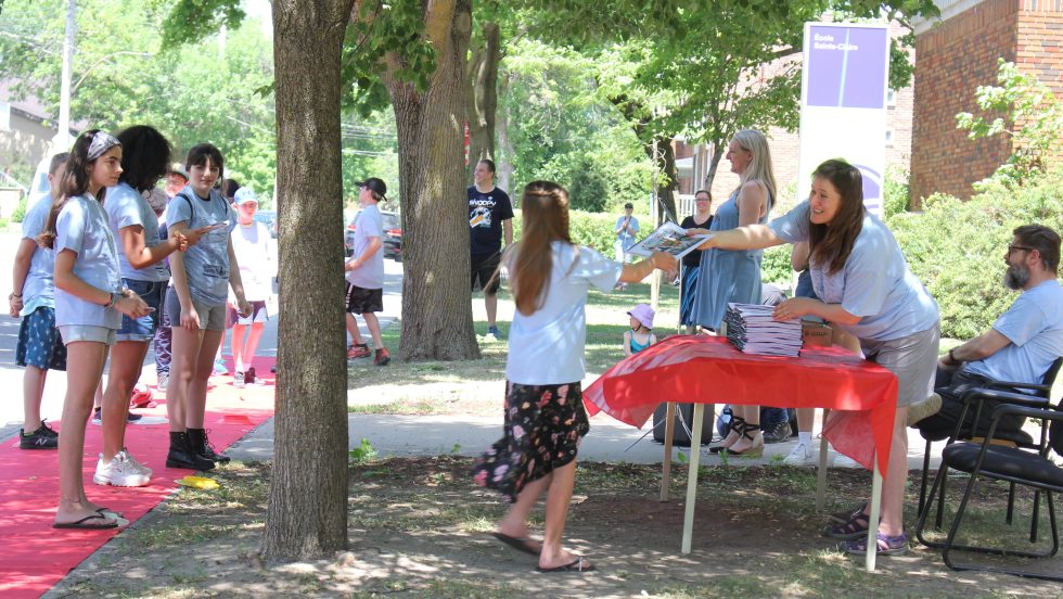 Les élèves de 6e année reçoivent leur album de finissant sur le tapis rouge devant l’école Sainte-Claire.
