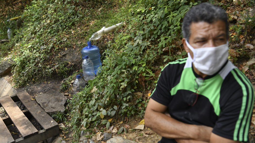 Un homme attend que de l'eau de source remplisse une bouteille, au Vénézuéla.