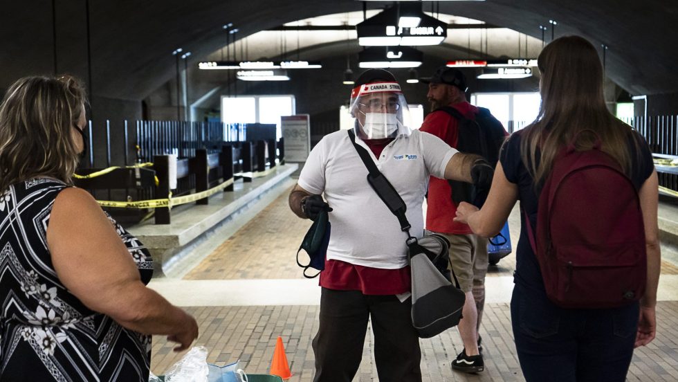 Des bénévoles distribuent des masques fournis par la STM dans une station de métro.