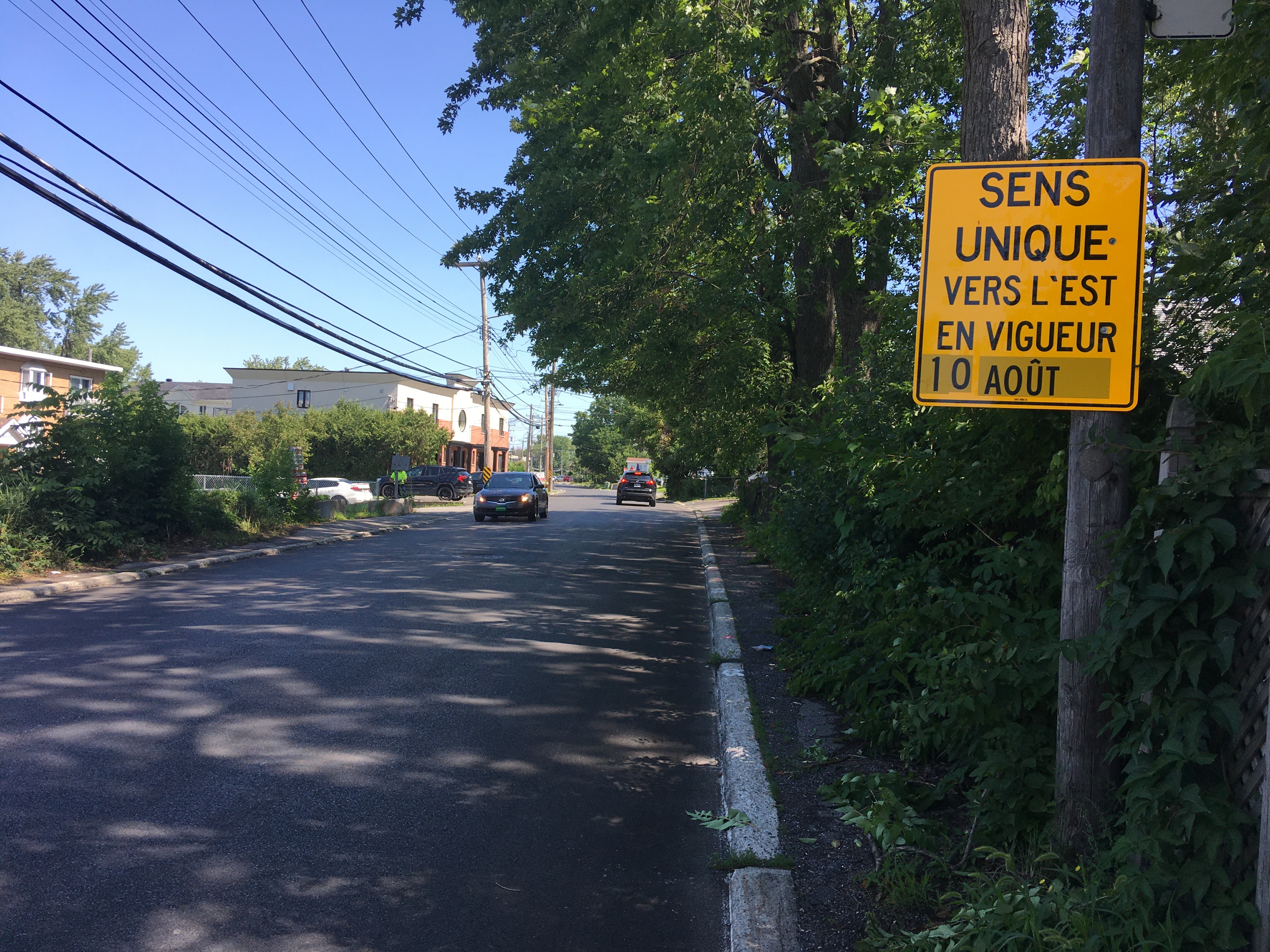 Une voiture circule vers l'ouest derrière un panneau de signalisation.