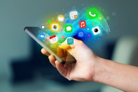 Main tenant un téléphone intelligent avec icônes colorées d'applications mobiles